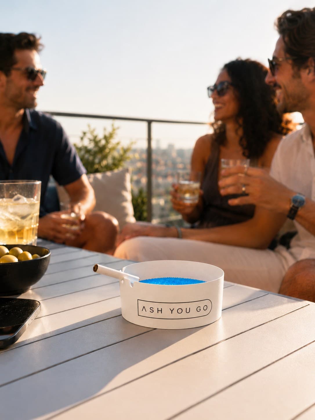 Friends on a rooftop balcony with an ASH YOU GO tray on the table