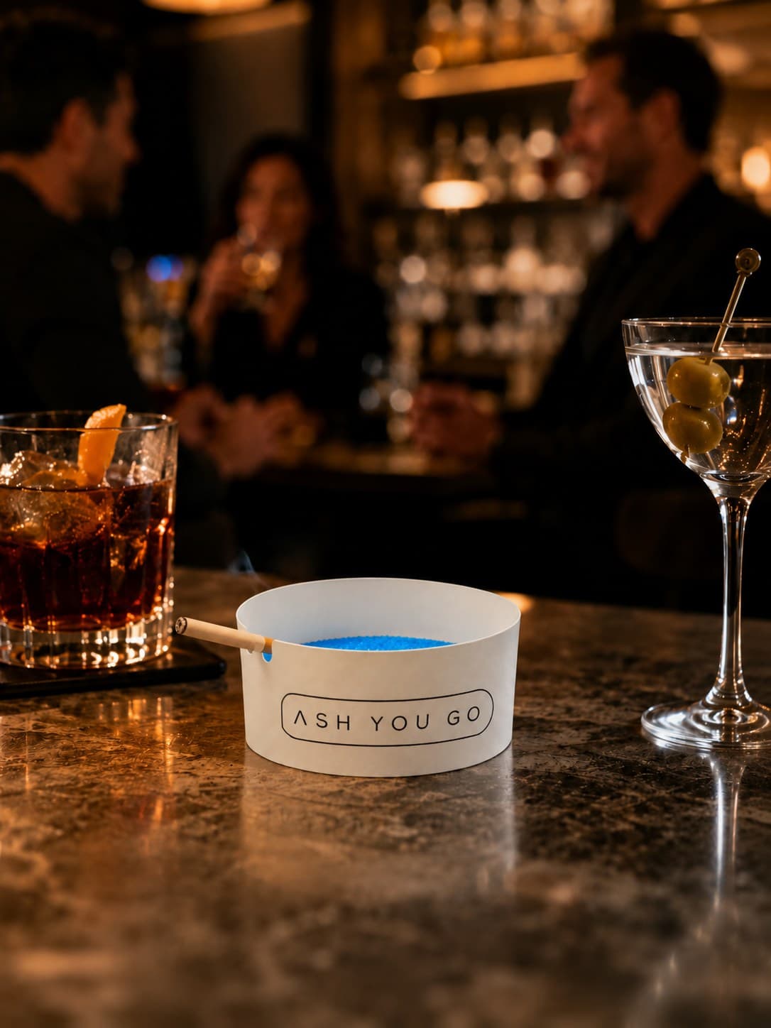 ASH YOU GO tray on a bar counter beside cocktails
